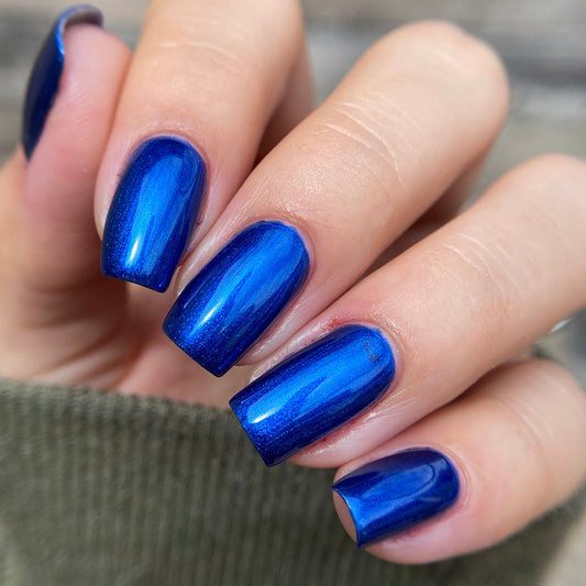 Close-up of a hand with blue nail polish on a blurred background