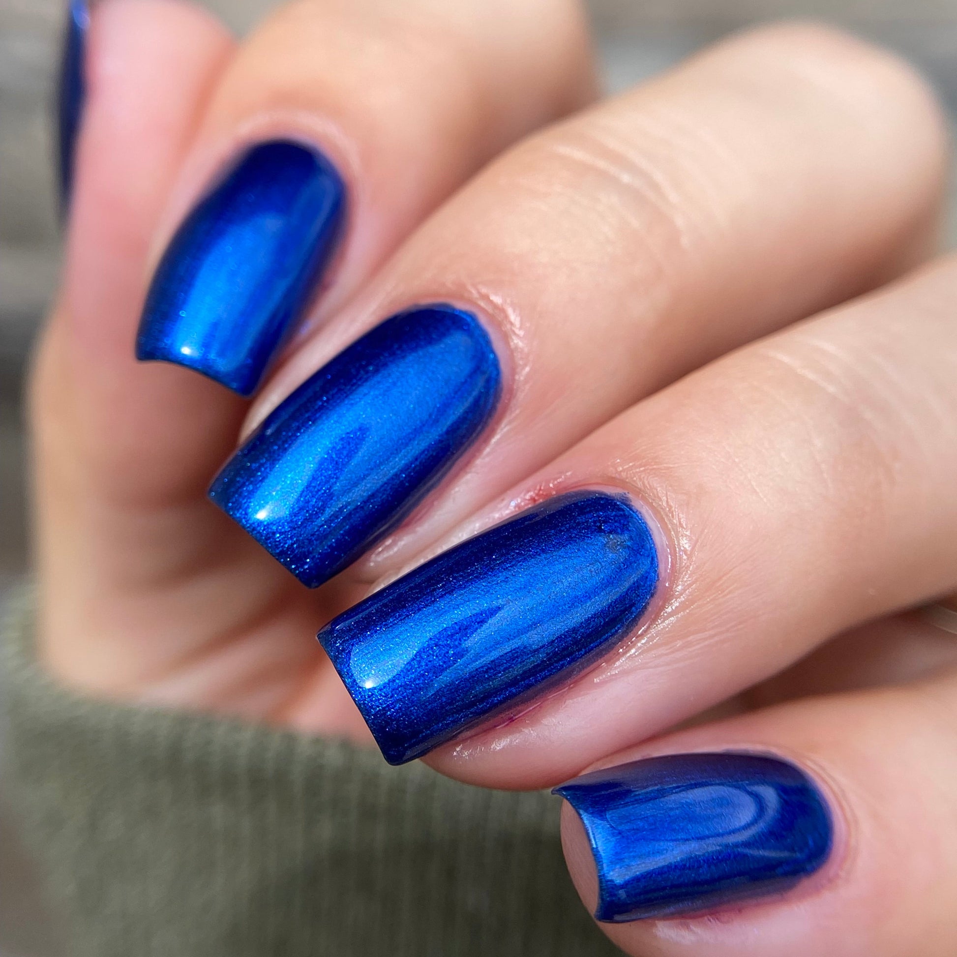 Close-up of a hand with blue nail polish on a blurred background