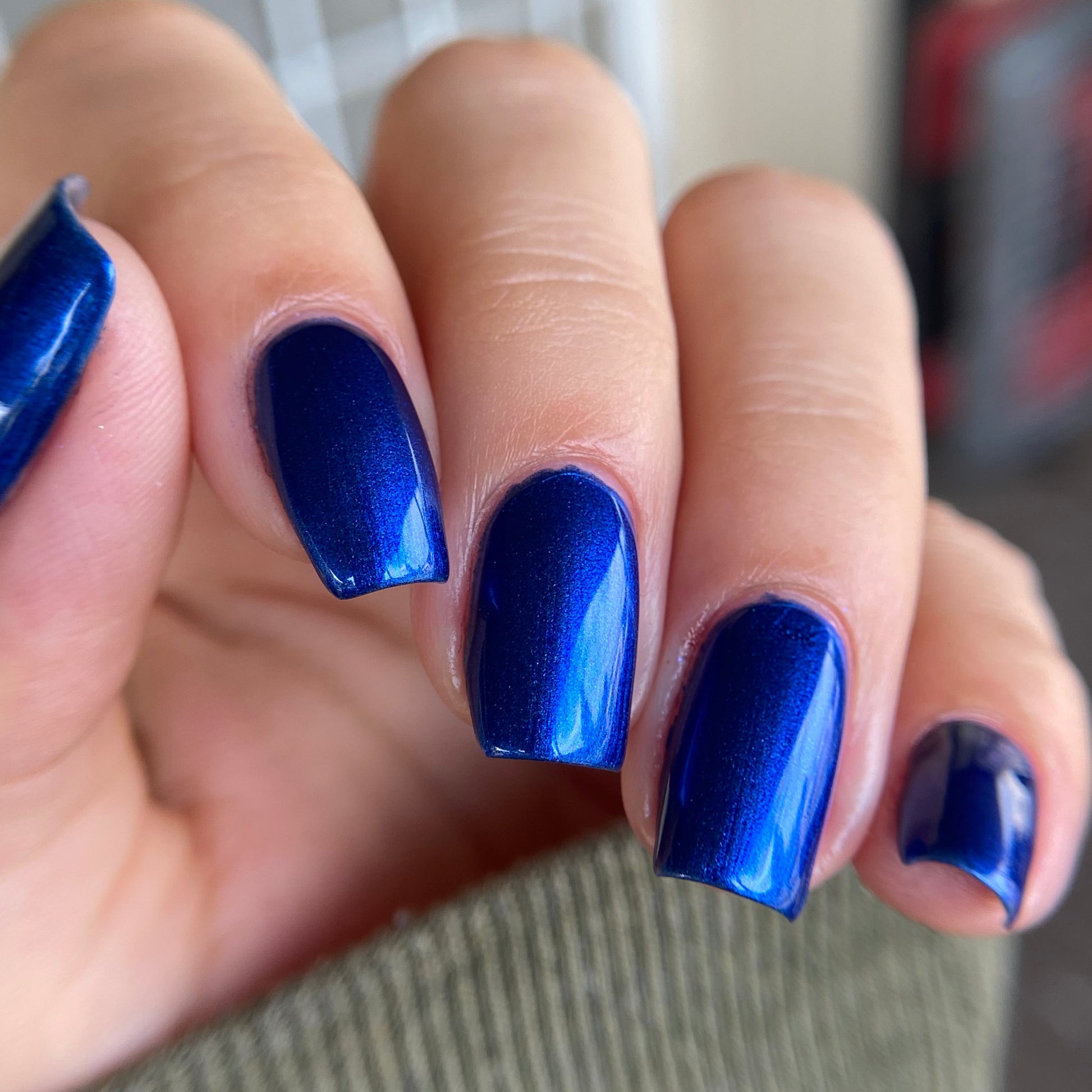 Close-up of a hand with blue nail polish on a blurred background
