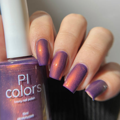 Hand with purple nail polish holding a bottle of PI Colors nail polish.