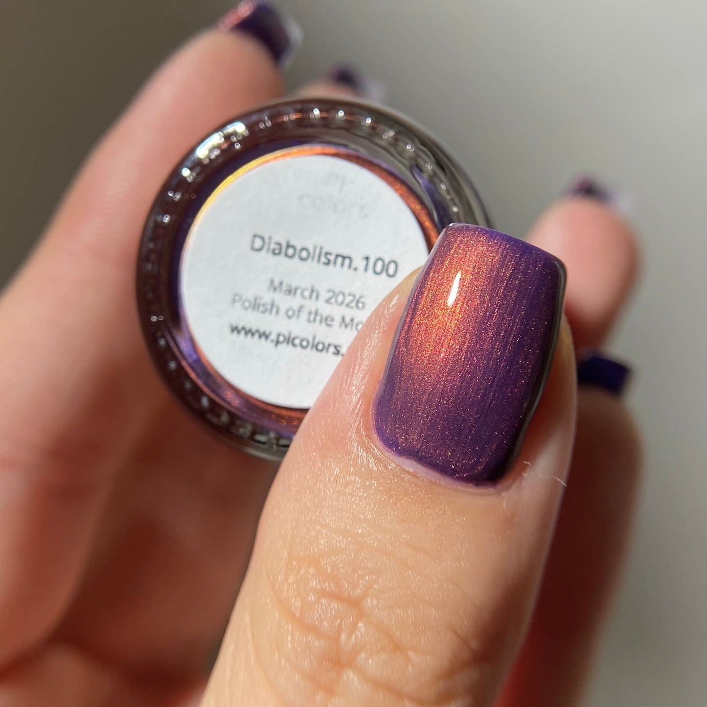 Hand with purple nail polish holding a jar of nail polish