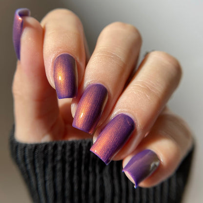Hand with purple nail polish on a neutral background