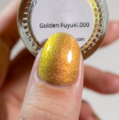 A close-up shot of a fingernail adorned with the luxurious PI Colors nail polish in metallic gold holo glitter, positioned beside a bottle labeled "Golden Fuyuki.000." The polish showcases a dazzling, iridescent finish.