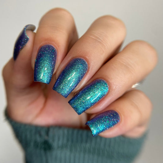 Hand with blue glittery nail polish on a plain background