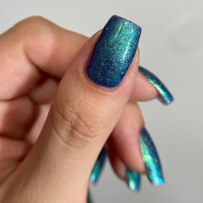 Hand with blue glittery nail polish on a plain background