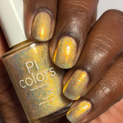 Hand with gold glitter nail polish holding a bottle of 'PI colors' nail polish.