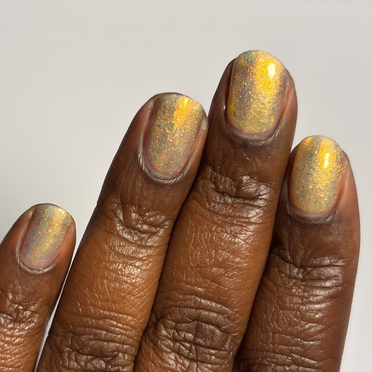 Hand with gold glitter nail polish on a plain background