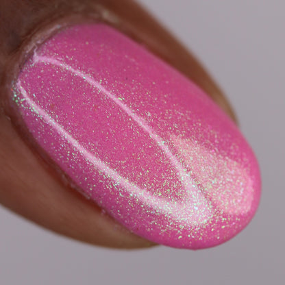 A close-up of a fingernail painted with PI Colors' Mint and Summer.100, a handmade pink nail polish with fine iridescent glitter, subtle colorshifting shimmer, and a smooth, glossy finish.