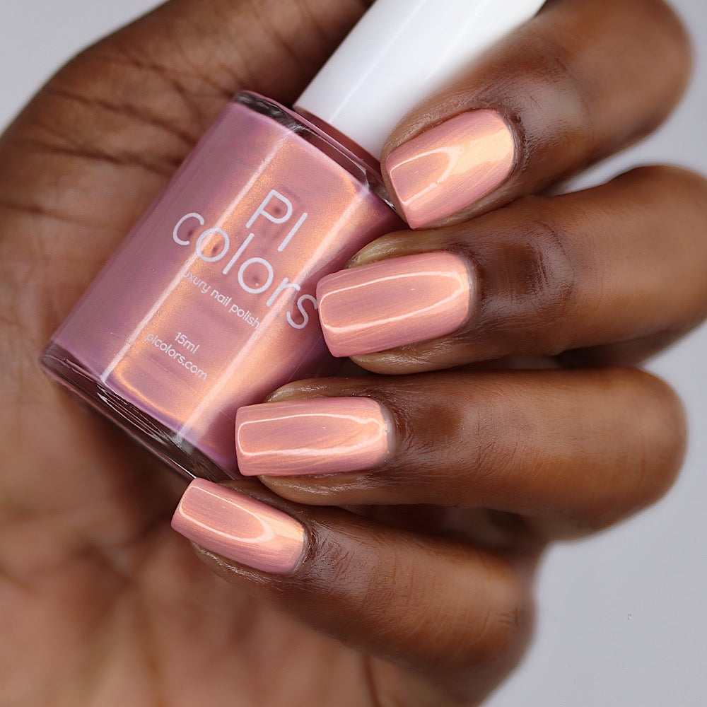 Hand holding a bottle of PI Colors nail polish with matching pink nails.