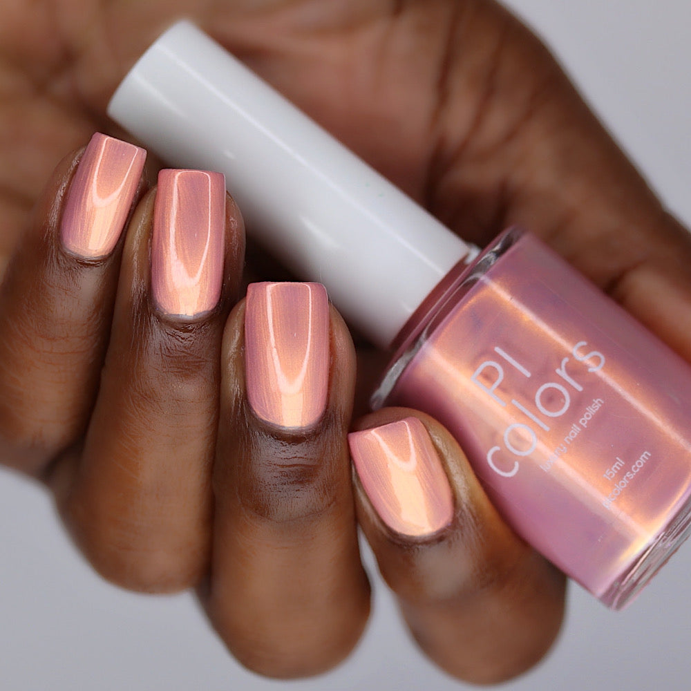 Hand with pink nail polish holding a bottle of PI Colors nail polish.