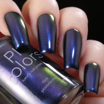 A close-up shot captures a hand adorned with long nails painted in a luxurious multichrome nail polish that shifts between captivating blue and green hues, reminiscent of 90s nostalgia. In the other hand, a matching bottle labeled "PI Colors" holds the vibrant shade known as "Judge None Choose One.000.