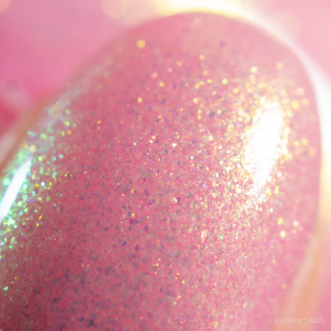 Close-up of a fingernail painted with PI Colors Lemon Pink Sugar Cookie.422, a handmade light pink polish featuring multicolored glitter and iridescent sparkles that shimmer under bright light.