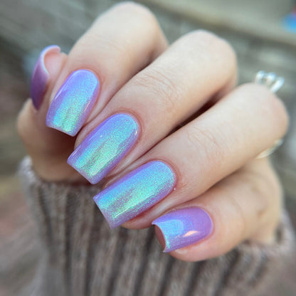 Hand with iridescent purple nail polish on a blurred background