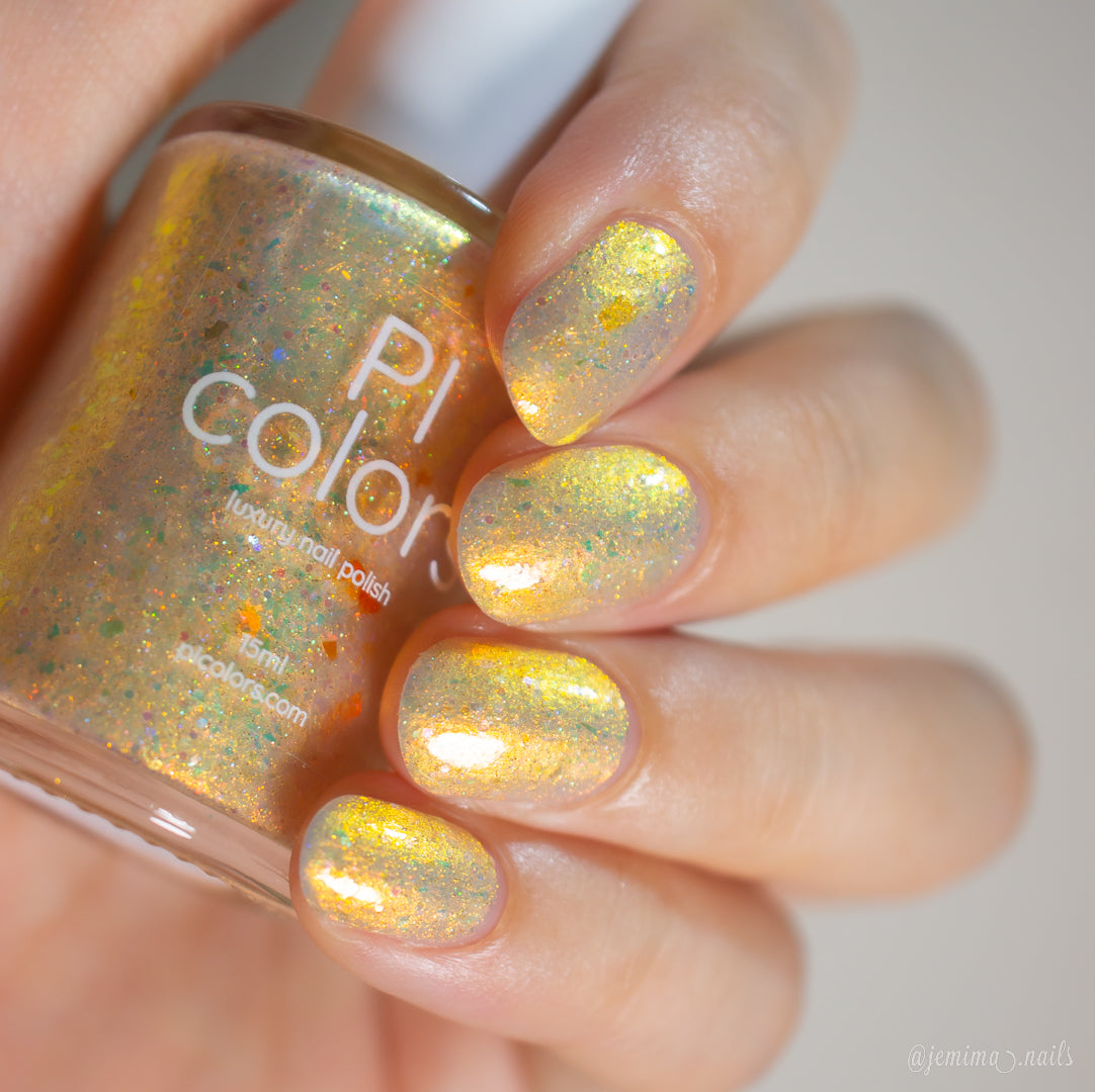 Hand with glittery yellow nail polish holding a bottle of PI color nail polish.