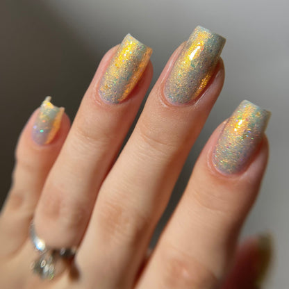 Hand with glittery nail polish on a neutral background