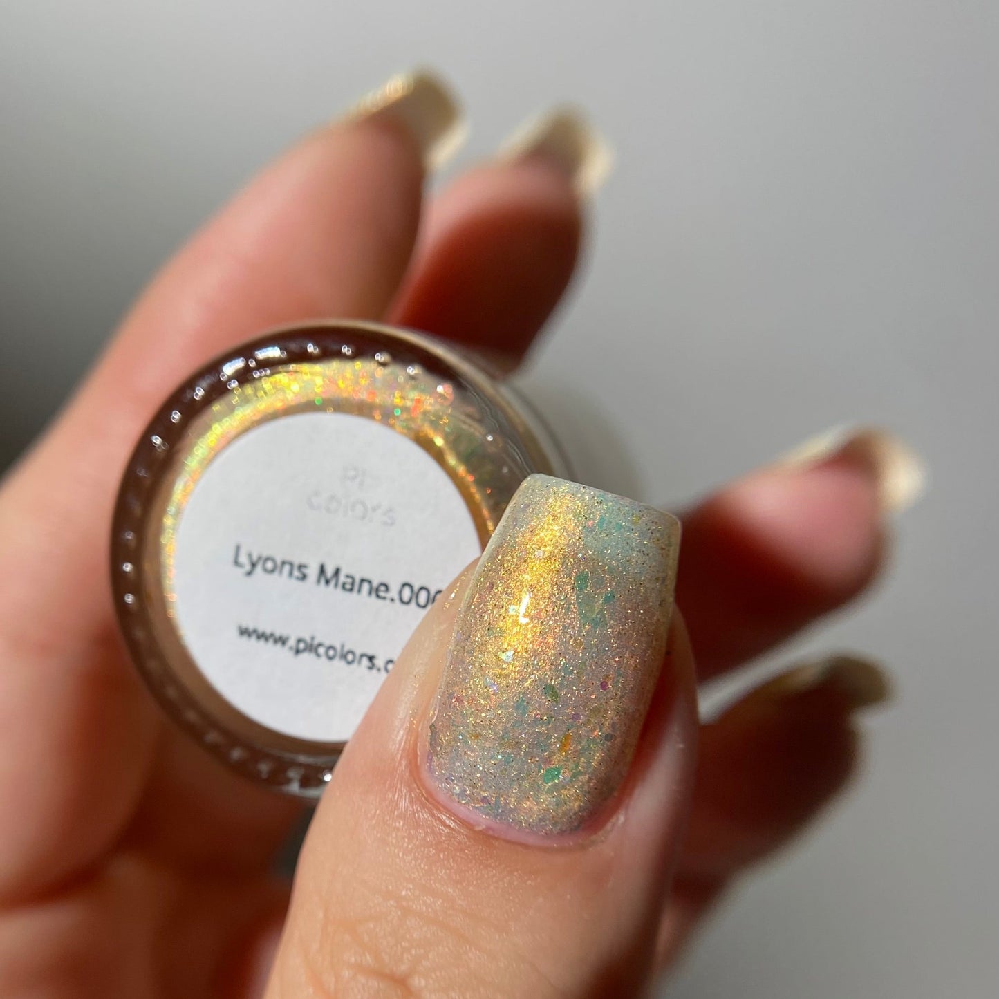 Hand holding a glittery nail polish jar with a blurred background