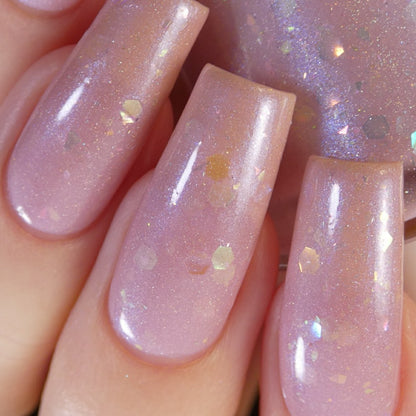 A close-up of a hand showcases long, glossy nails painted with PI Colors' Special Week.000 Pink Nail Polish, adorned with iridescent rainbow flakies, reminiscent of the vibrant energy in Uma Musume Pretty Derby.