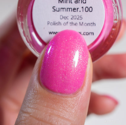A close-up of a hand with a fingernail painted in bright, colorshifting pink shimmer polish. In the background, there’s a round bottle labeled "Mint and Summer.100" from PI Colors.