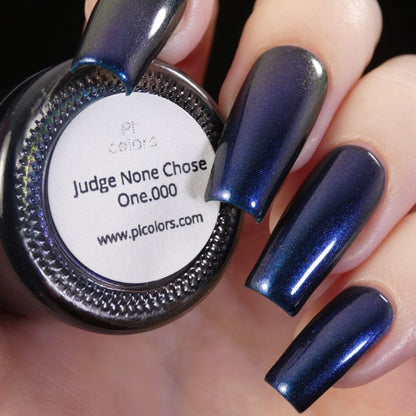 Close-up of a hand with long, dark metallic blue nails, holding a nail polish bottle labeled "Judge None Choose One.000" by PI Colors. This PI Colors Luxury Nail Lacquer features a multichrome finish that perfectly complements the nails, evoking an air of 90s nostalgia.