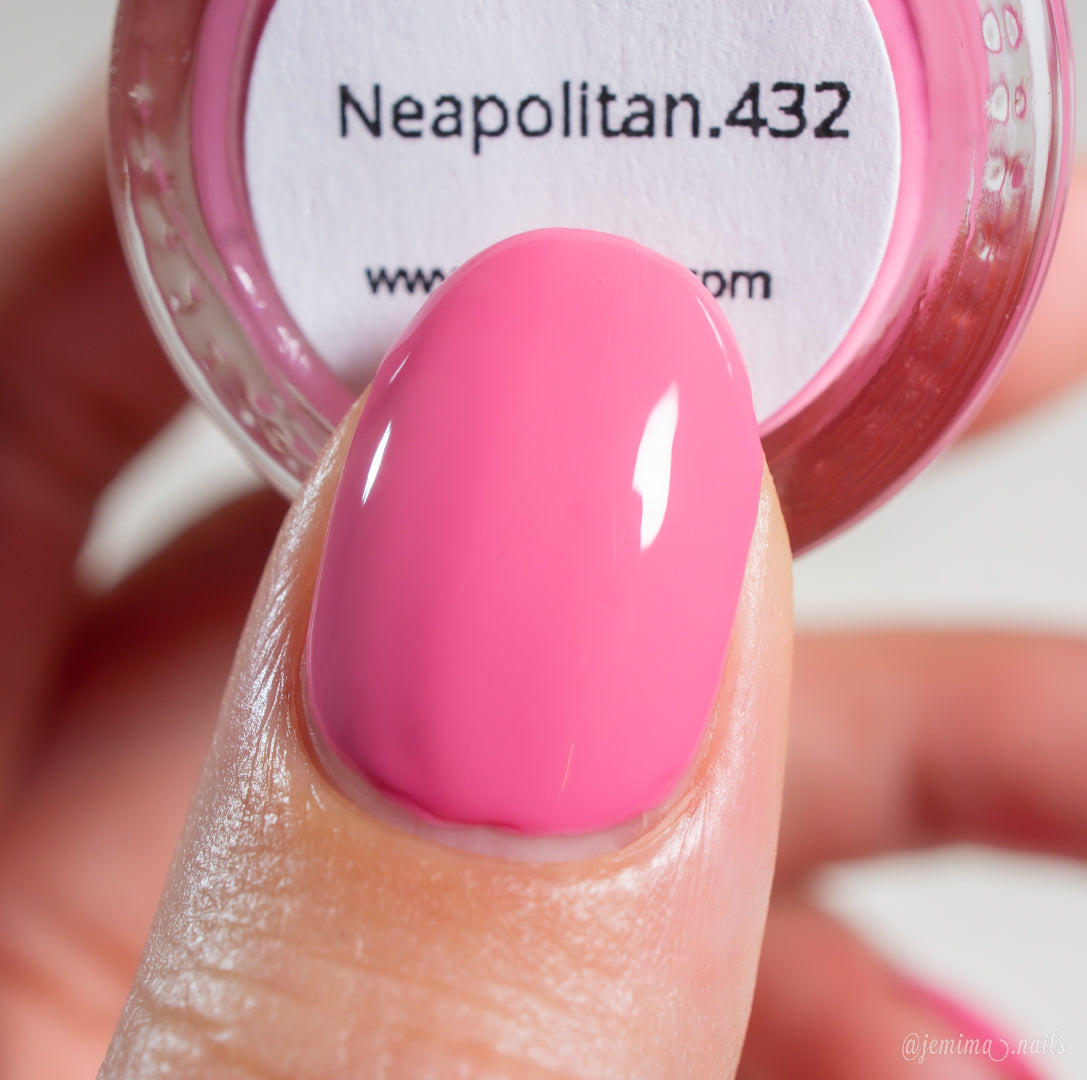 A thumb painted with glossy pink nail polish is held near a bottle labeled "Neapolitan.432" by PI Colors, perfectly matching the vibrant shade of this luxury nail lacquer.