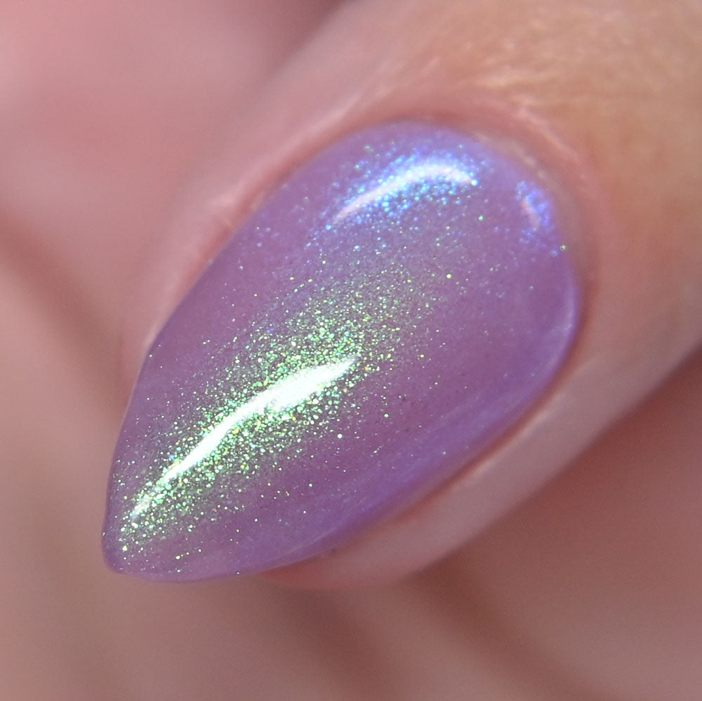 Close-up of a purple nail with green glitter on a blurred background