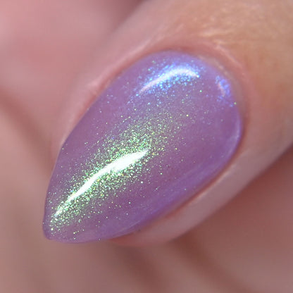 Close-up of a purple nail with green glitter on a blurred background