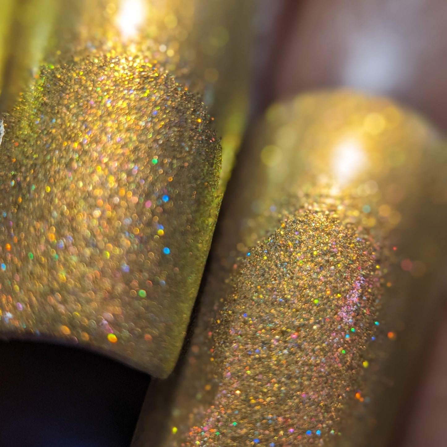 Close-up of fingernails painted with PI Colors' Golden Fuyuki.000, a luxury nail polish featuring metallic gold holo glitter. The nails shimmer with a rainbow effect in the light, revealing a sparkling and textured surface.