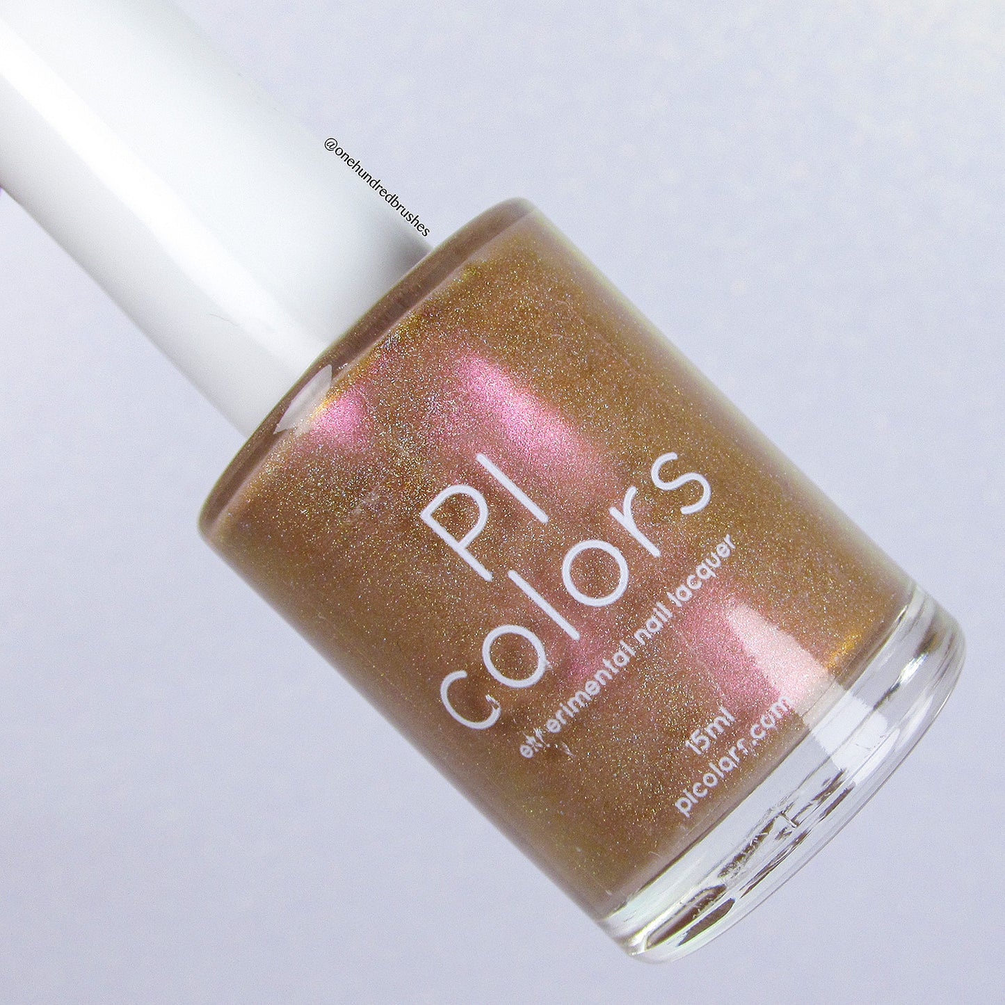 A bottle of PI Colors nail lacquer named "Phoenix.087," featuring a brown hue with pink shimmer and holographic glitter, comes in a 15 ml size. The cap is white, and the background displays a subtle gradient.