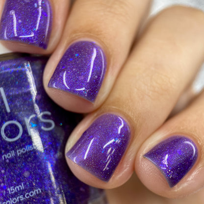 Close-up of manicured nails painted with PI Colors' Purple Smoke.001 purple nail polish in a sparkling jelly finish. A hand holds the bottle, displaying a matching hue adorned with holo purple glitters that produce a glossy, shimmering effect on the nails.