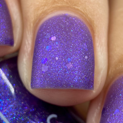 Close-up of fingers adorned with PI Colors' Purple Smoke.001 Nail Polish, showcasing a purple jelly finish with small, multicolored holo purple glitters. The texture appears smooth and shiny under the light.