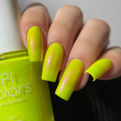 A close-up of a hand with neon yellow-green manicured nails holding an OPI Colors nail polish bottle in the same bright lime shade.