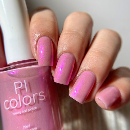 Pink nail polish bottle with matching nails against a neutral background