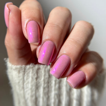 Close-up of a hand with pink nail polish on a neutral background
