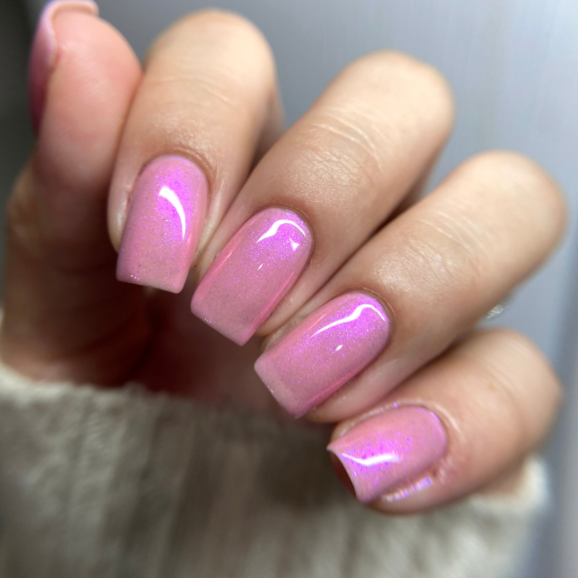 Close-up of a hand with pink nail polish on a blurred background