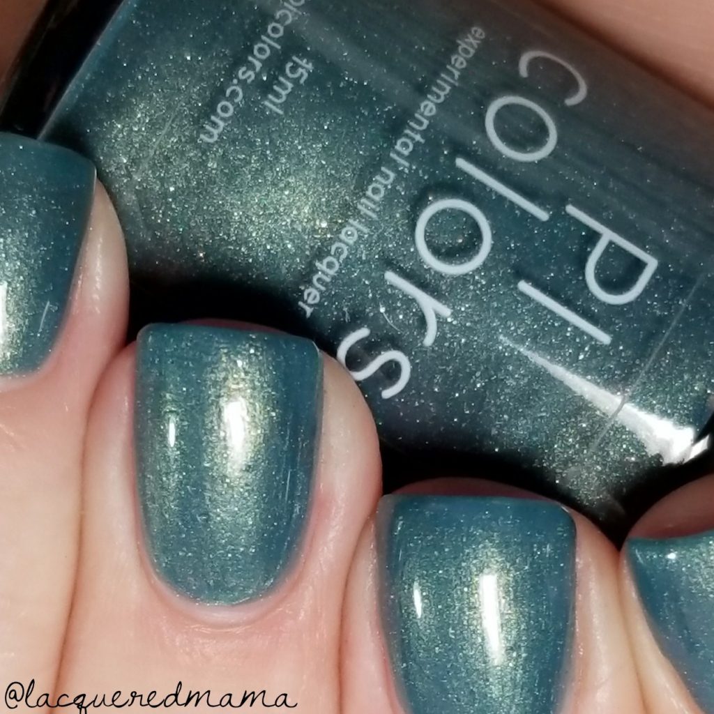 Close-up of fingernails adorned with mesmerizing shimmering teal from the PI Colors Sea Kelp.092 Green Nail Polish. In the background, a bottle displaying the same captivating polish catches the light with its subtle sparkle, alongside a glimpse of an Instagram username's handle.