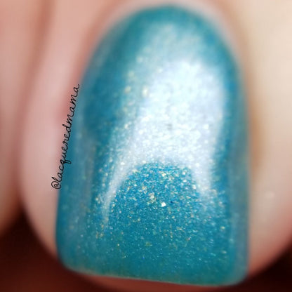 A close-up of a fingernail featuring PI Colors' PavoC.023, a 10-free turquoise nail polish with a gradient effect and delicate golden sparkles. The polish boasts a glossy finish, with the blurred background highlighting the handcrafted nail design.