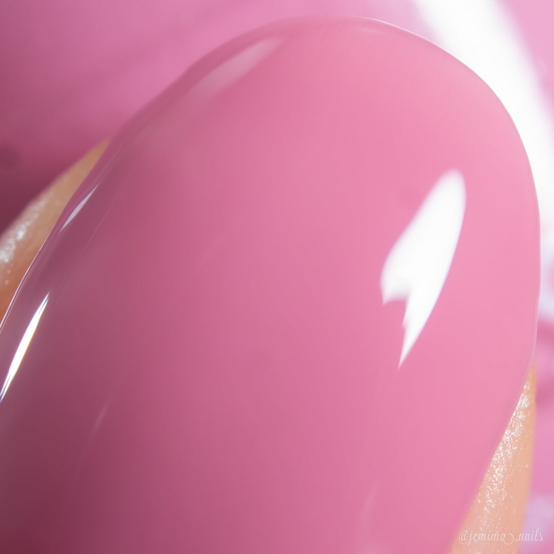 A close-up of a fingernail painted with PI Colors Pink Biscotti.462, a glossy brownish pink creme polish, reflecting light and revealing a smooth, shiny finish.