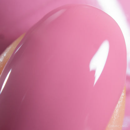 A close-up of a fingernail painted with PI Colors Pink Biscotti.462, a glossy brownish pink creme polish, reflecting light and revealing a smooth, shiny finish.