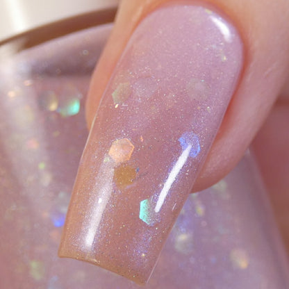 A close-up of a fingernail adorned with PI Colors' Special Week.000 Pink Nail Polish, showcasing a luxurious, glittery iridescent finish with a pinkish hue, complemented by reflective hexagonal flakes for a glossy, shimmering effect.