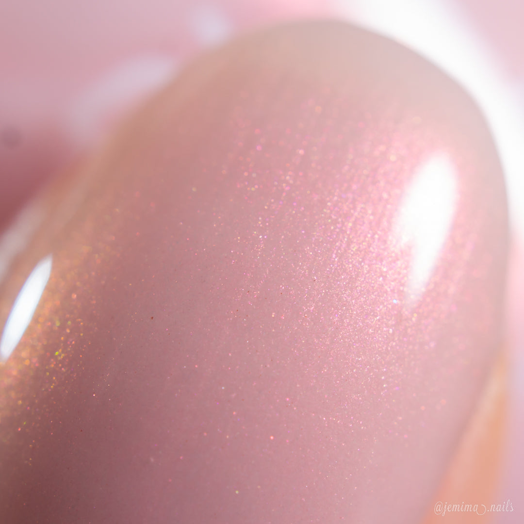 Close-up of a fingernail painted with PI Colors Snickerdoodle.405, a glossy, shimmery pale pink polish that reflects light and delivers a smooth, sparkling finish—ideal for fans of luxury nail lacquers.