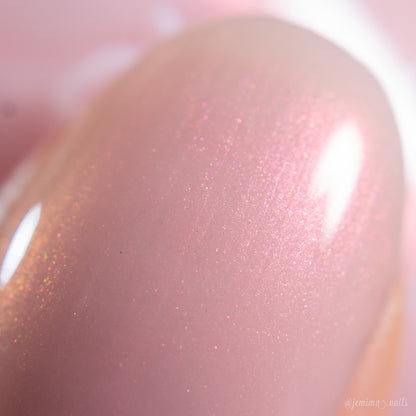 Close-up of a fingernail painted with PI Colors Snickerdoodle.405, a glossy, shimmery pale pink polish that reflects light and delivers a smooth, sparkling finish—ideal for fans of luxury nail lacquers.