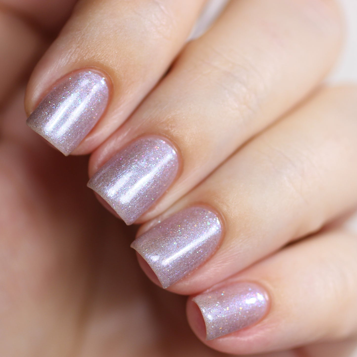 Close-up of a hand with well-manicured nails painted in PI Colors' Snow Cherries From France.101 Purple Nail Polish, featuring a hint of holographic glitter. The nails have a glossy finish and are shaped in a neat square style, complementing the light skin tone beautifully.