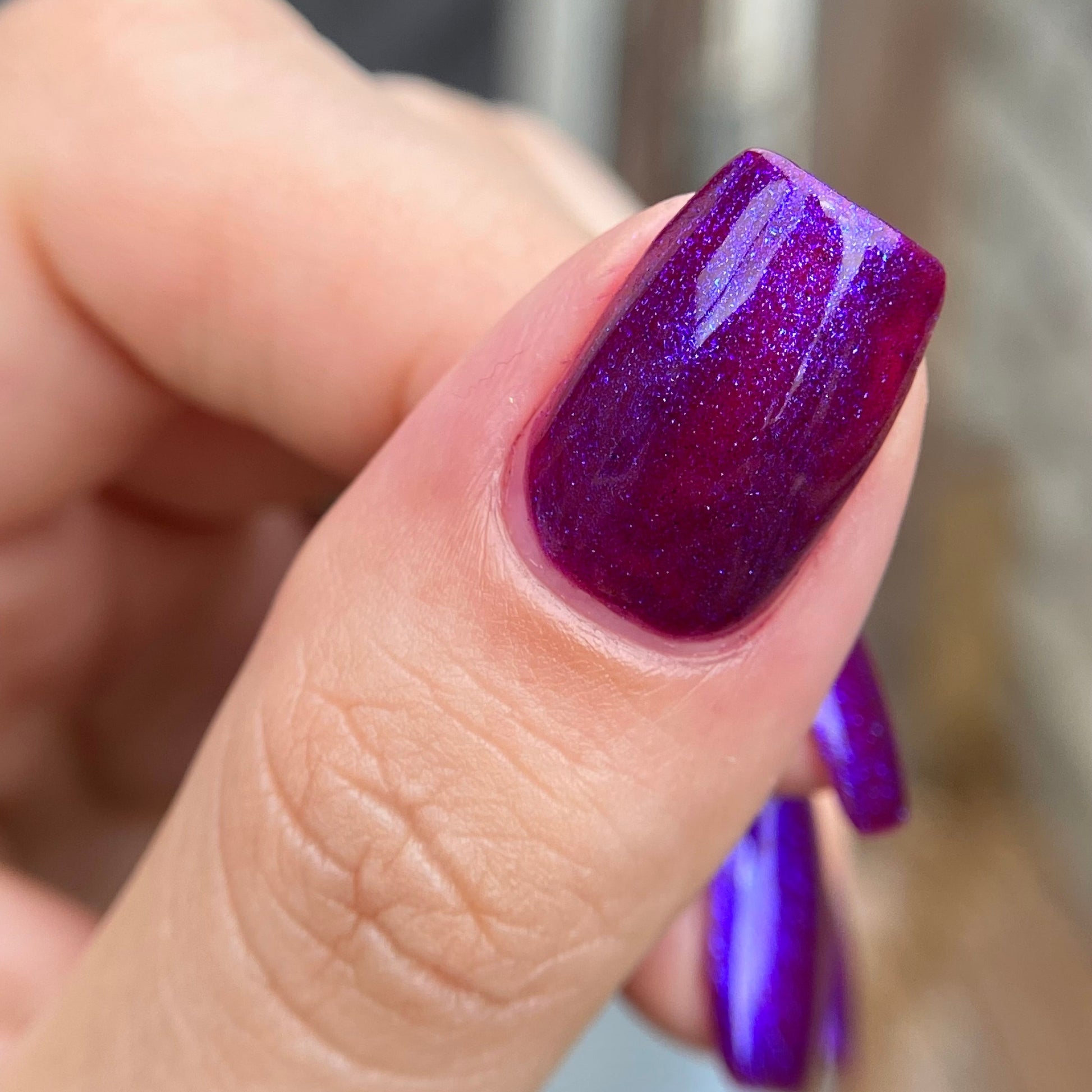 Close-up of a hand with a purple nail polish on a blurred background