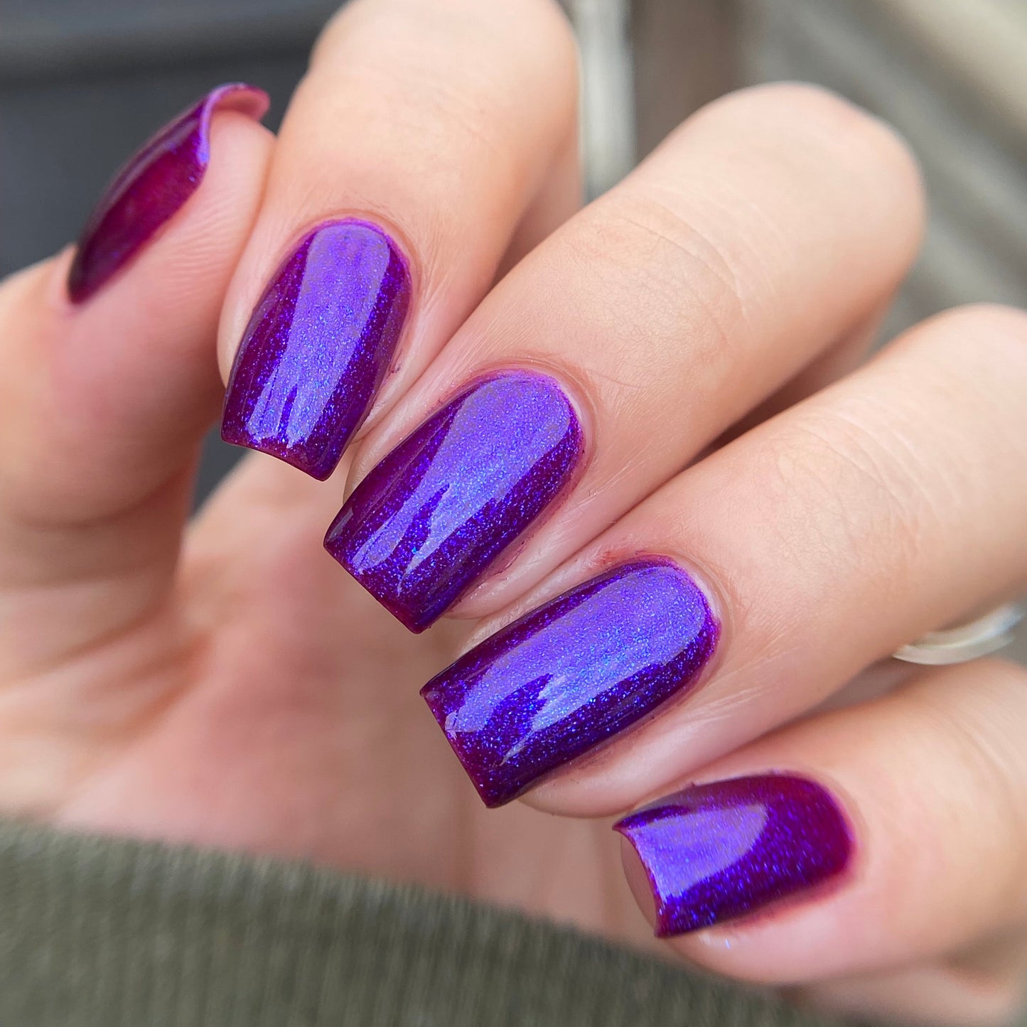 Hand with purple nail polish on a blurred background
