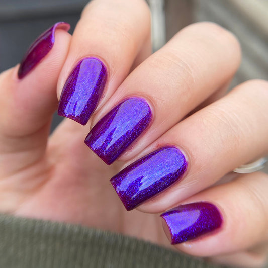 Hand with purple nail polish on a blurred background