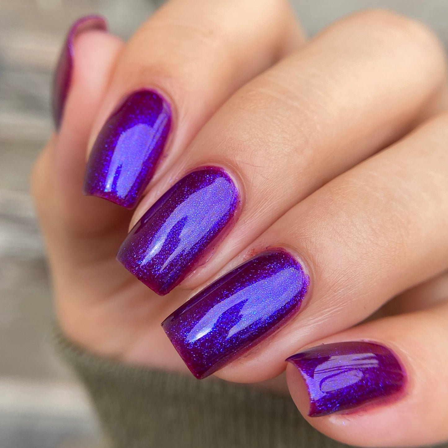 Close-up of a hand with purple nail polish on a blurred background