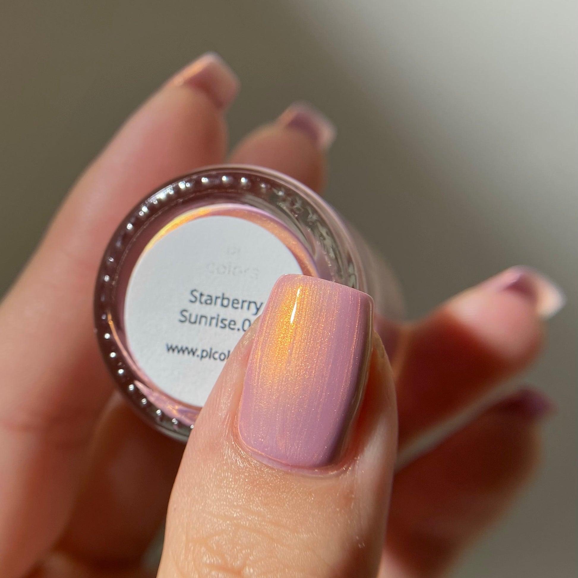 Hand holding a small container of cosmetic powder with 'Starberry Sunrise' label.