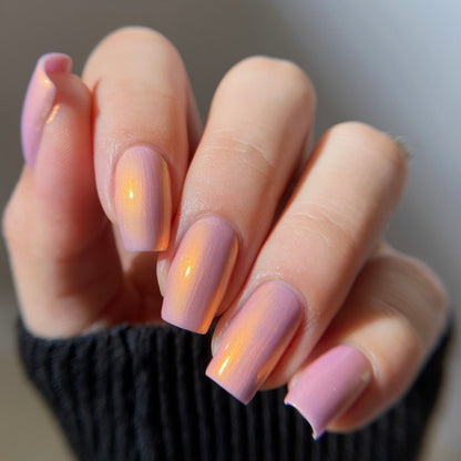 Close-up of a hand with pink nail polish on a neutral background