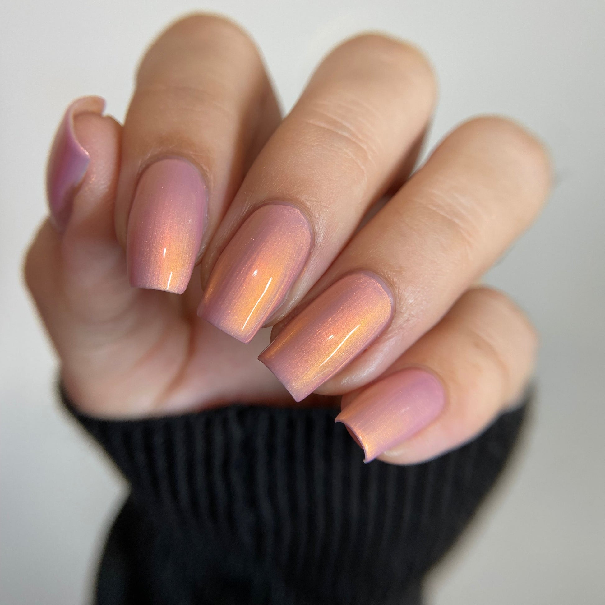 Hand with pink gradient nail polish on a neutral background