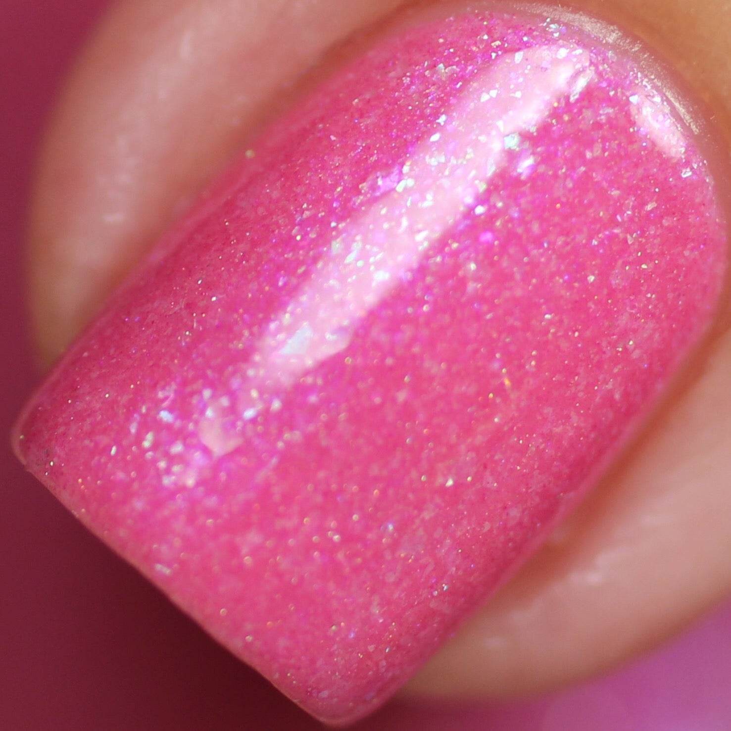 A close-up of a fingernail painted with PI Colors' Strawberry Sundae.002 Pink Nail Polish unveils a glossy pink finish accentuated by shimmering holographic powder. The polish catches the light, creating a dazzling effect, while the surrounding skin looks smooth and expertly manicured.